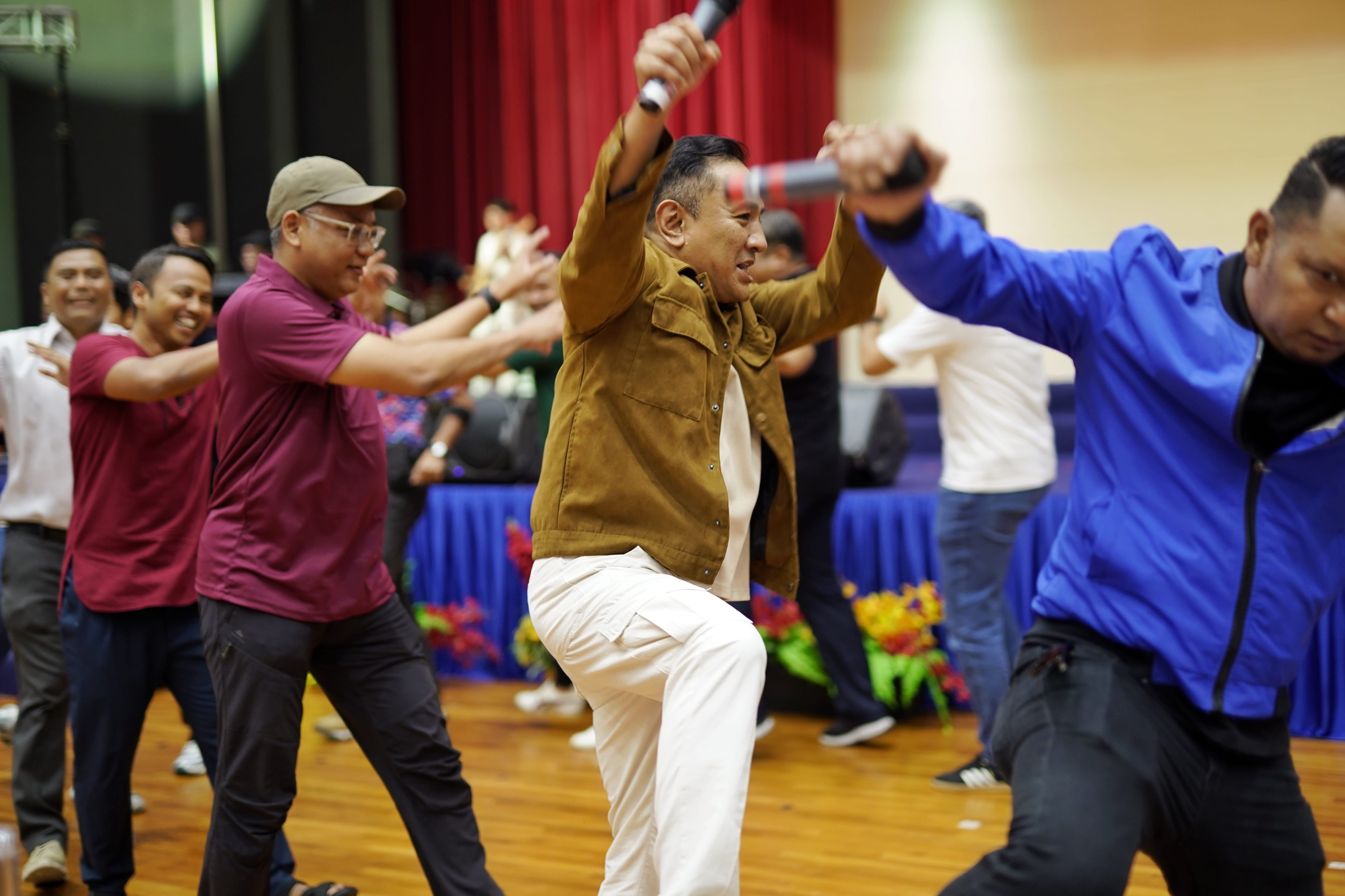 Participants raise their arms and dance energetically together in an interactive performance.